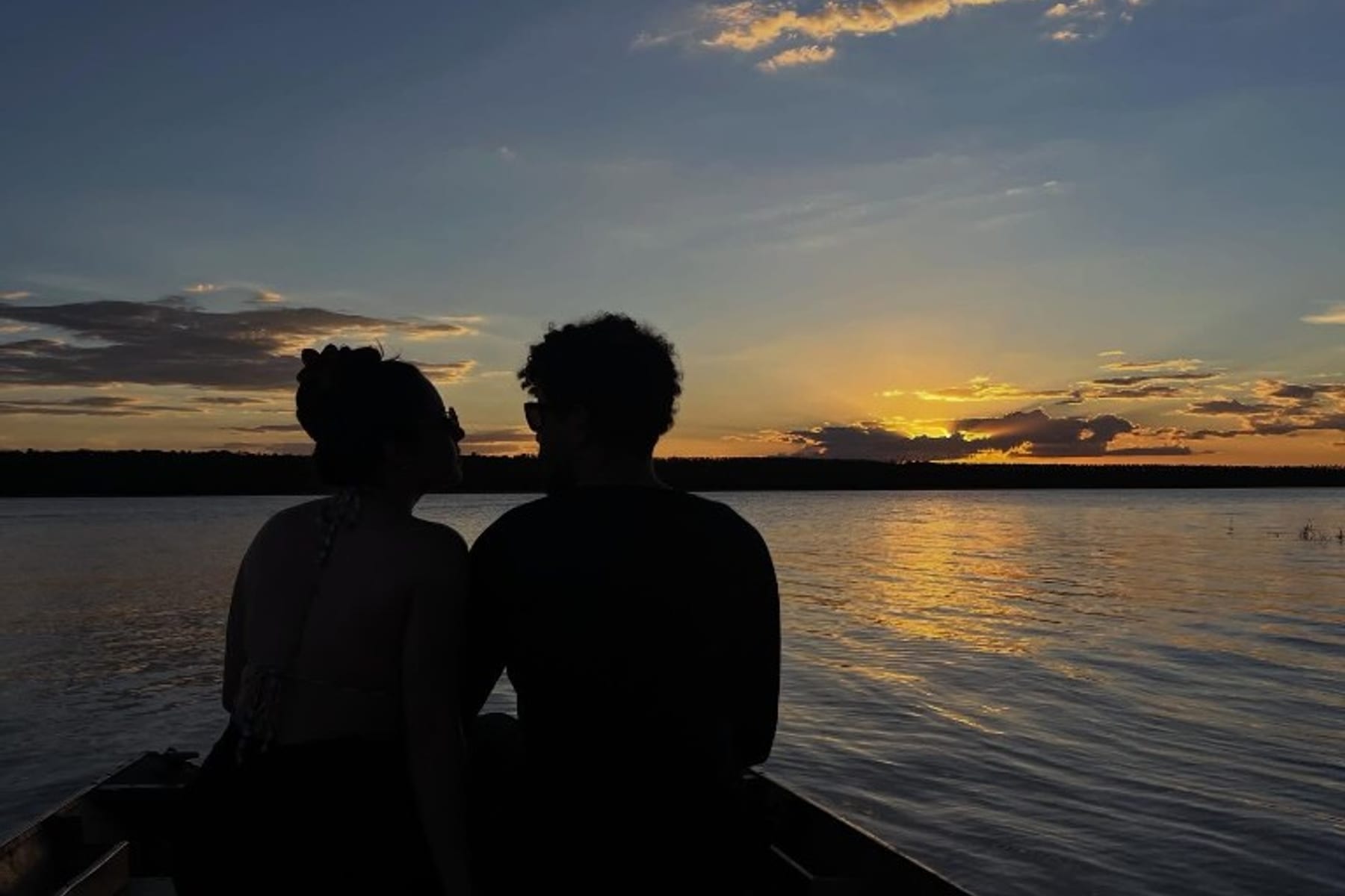 Silhueta do casal em barco ao pôr do sol